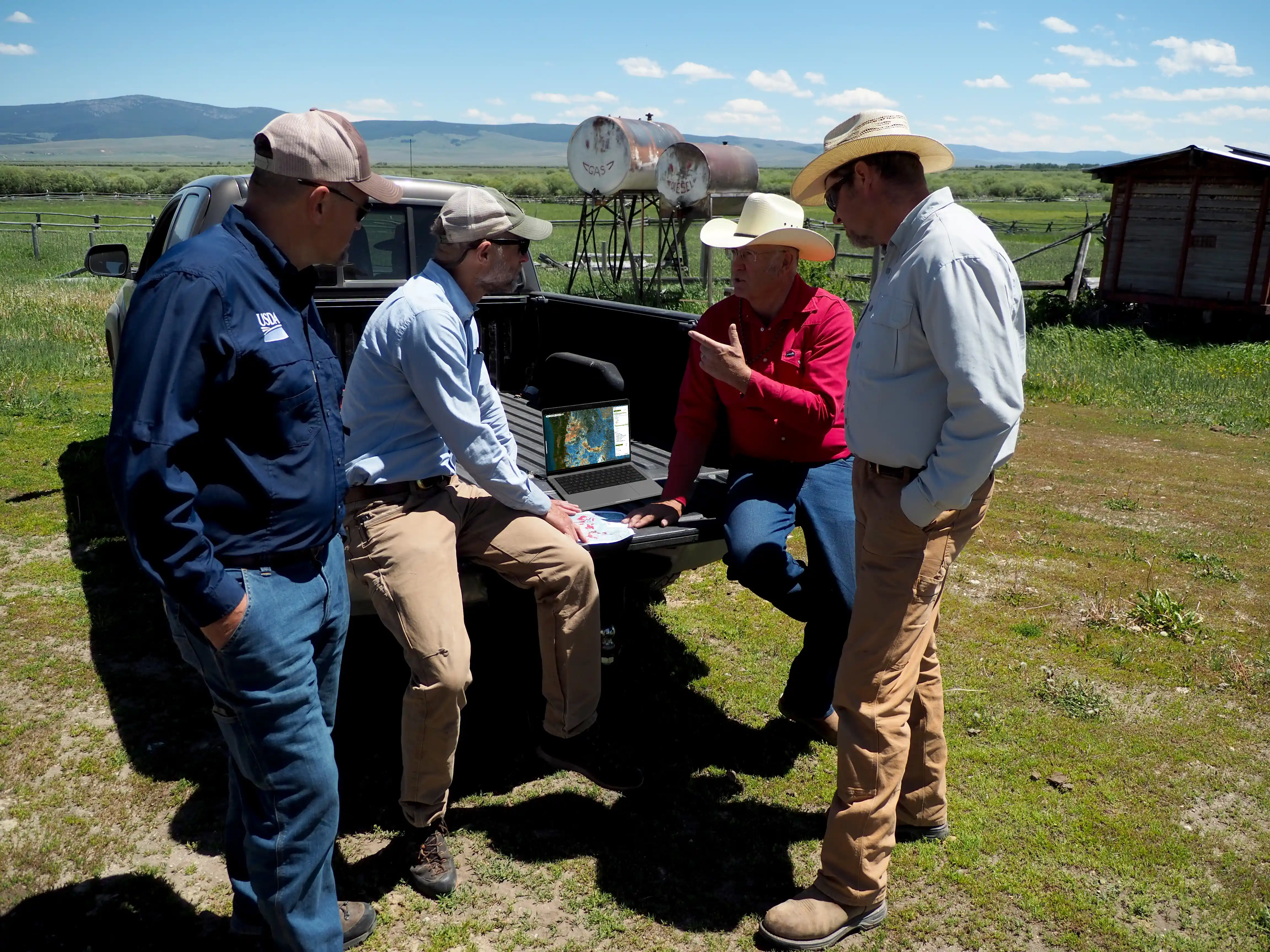 Land managers discussing treatment plans beside a pickup truck with an ISI map on a laptop