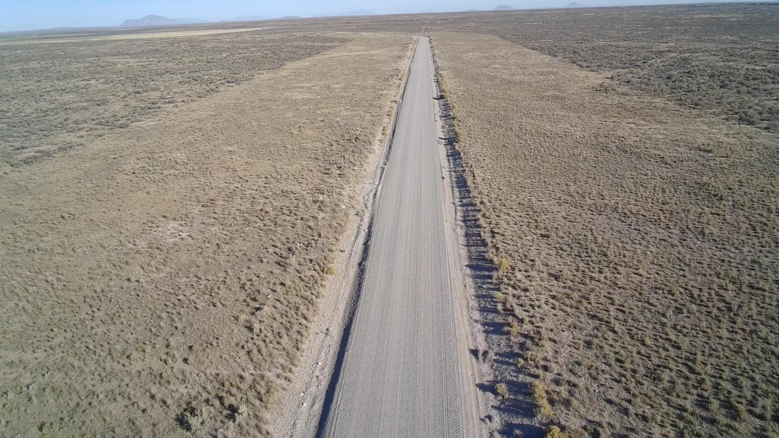 Aerial view of a wide fuel break along a gravel road through sagebrush rangeland.